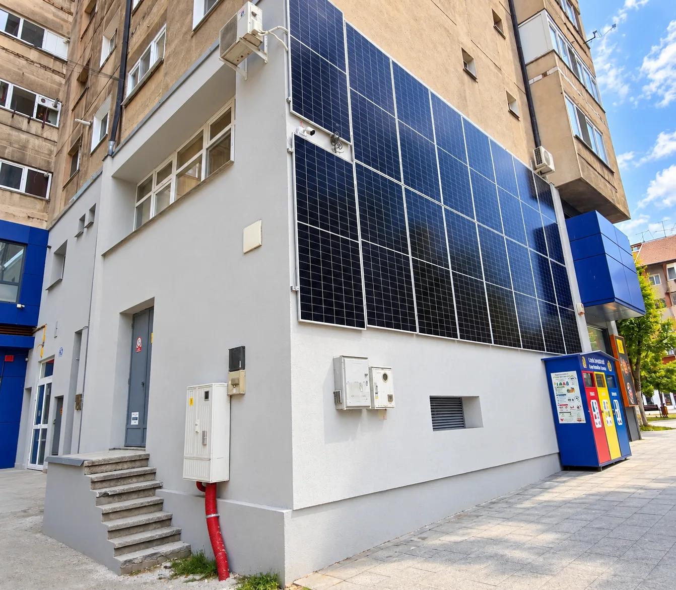 Spațiu comercial la parterul unui bloc, cu fațada finisată în gri și panouri fotovoltaice pe perete
